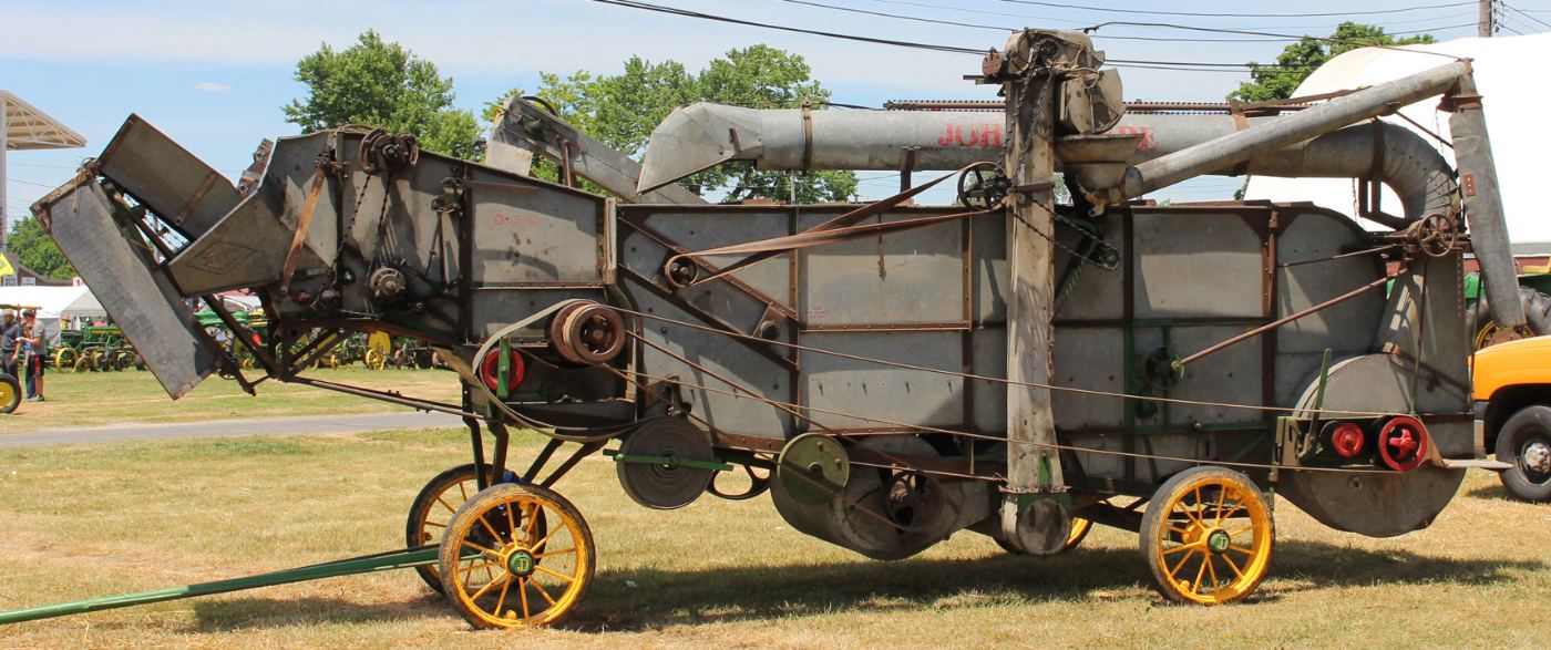 Restored John Deere threshing machine with yellow wheels
