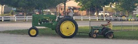 John Deere tractor towing a child on a small garden tractor