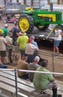 Spectators watching a John Deere tractor on a trailer