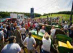 Large crowd gathered around tractors at an auction