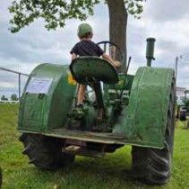Child sitting on the seat of a John Deere tractor