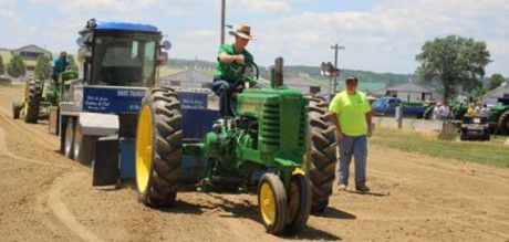 John Deere Model G pulling the sled, with an official walking alongside