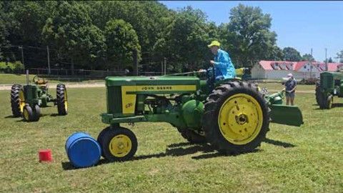 John Deere garden tractor game with a blue barrel