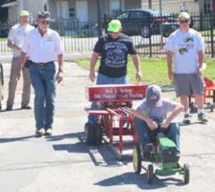 Child in the pedal tractor pull with officials watching