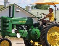 Driver on a John Deere tractor with a yellow umbrella