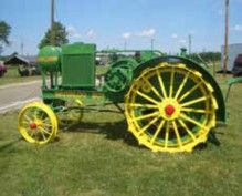 Early John Deere tractor with yellow spoked steel wheels
