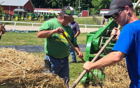 Volunteers pitching straw into a baler